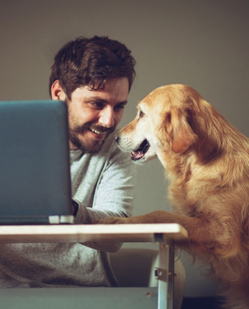 Man telewerkt met zijn hond naast zich